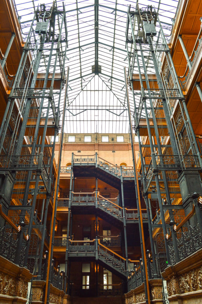 inside of Bradbury Building showcasing the skylights, orante ironwork, and decorated staircases and elevators
