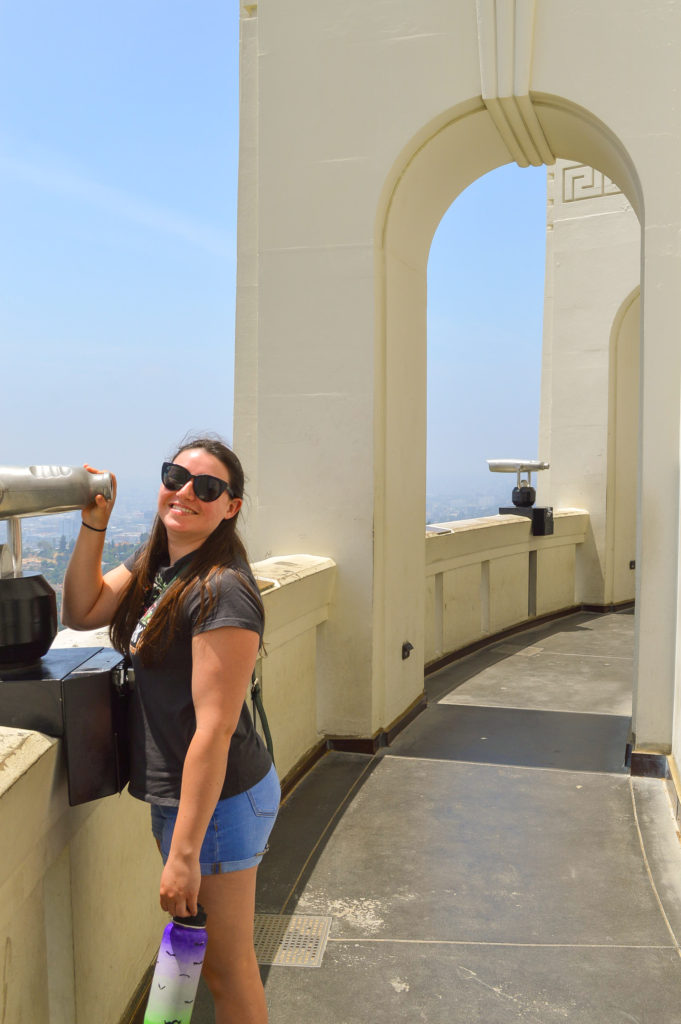 woman posing with a telescope at Griffith Observatory during the day