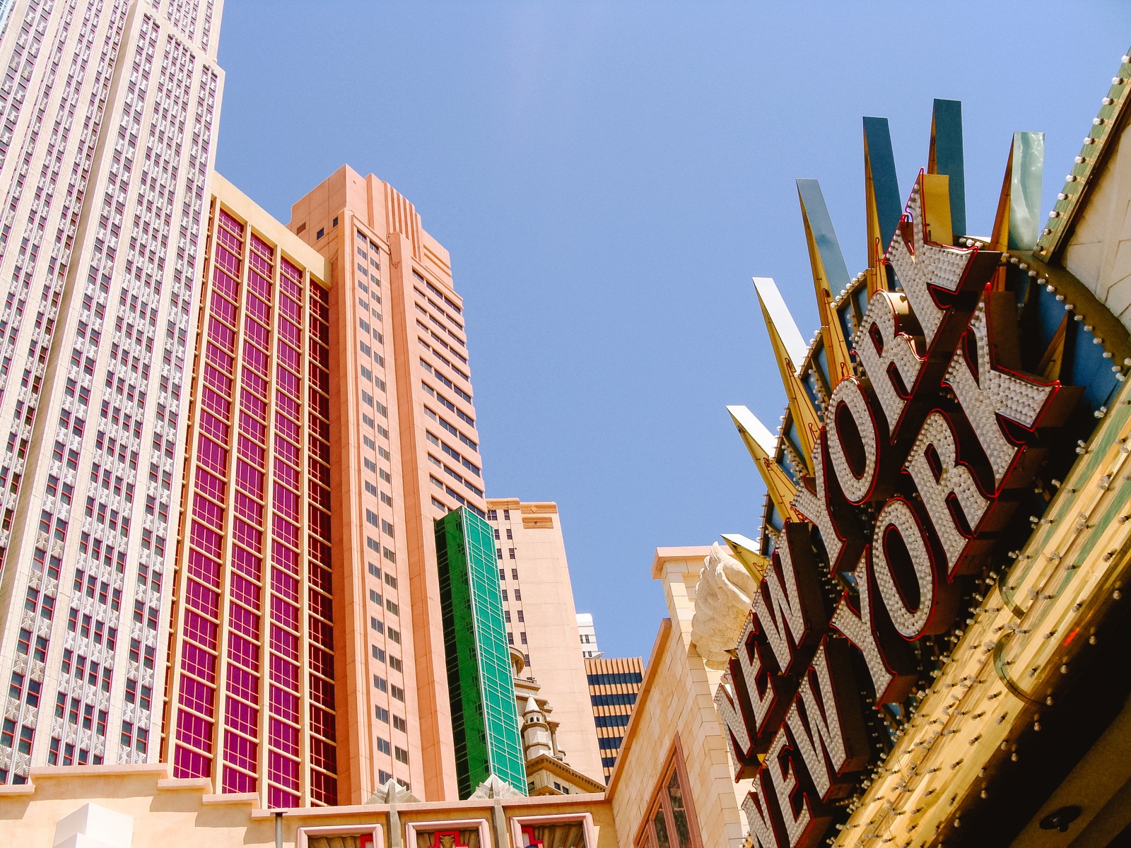 New York replica hotel during Day time with neon sign and skyscraper hotel towers in the background