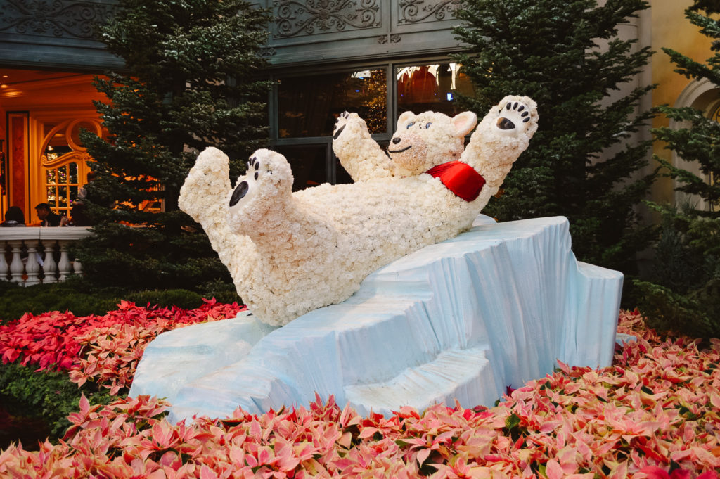 cute polar bear made of flowers in a garden display laying on a fake iceberg on a bed of pink flowers