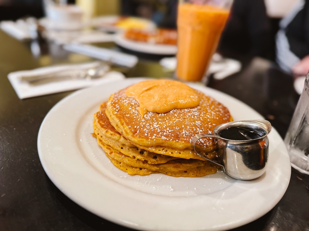 Stack of pumpkin pancakes with syrup and cream cheese frosting