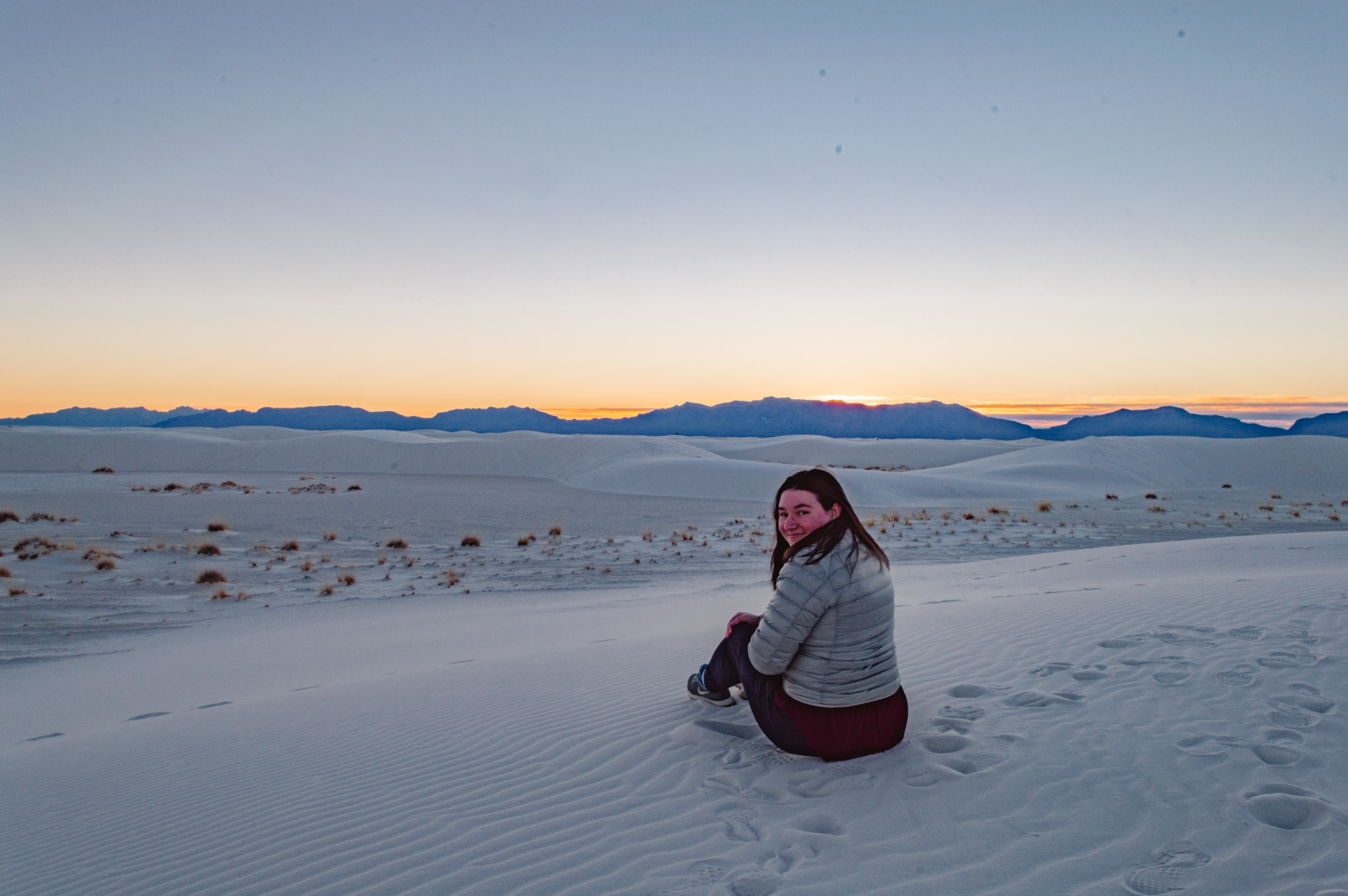 woman sitting on the white sand at White Sands National Park in New Mexico