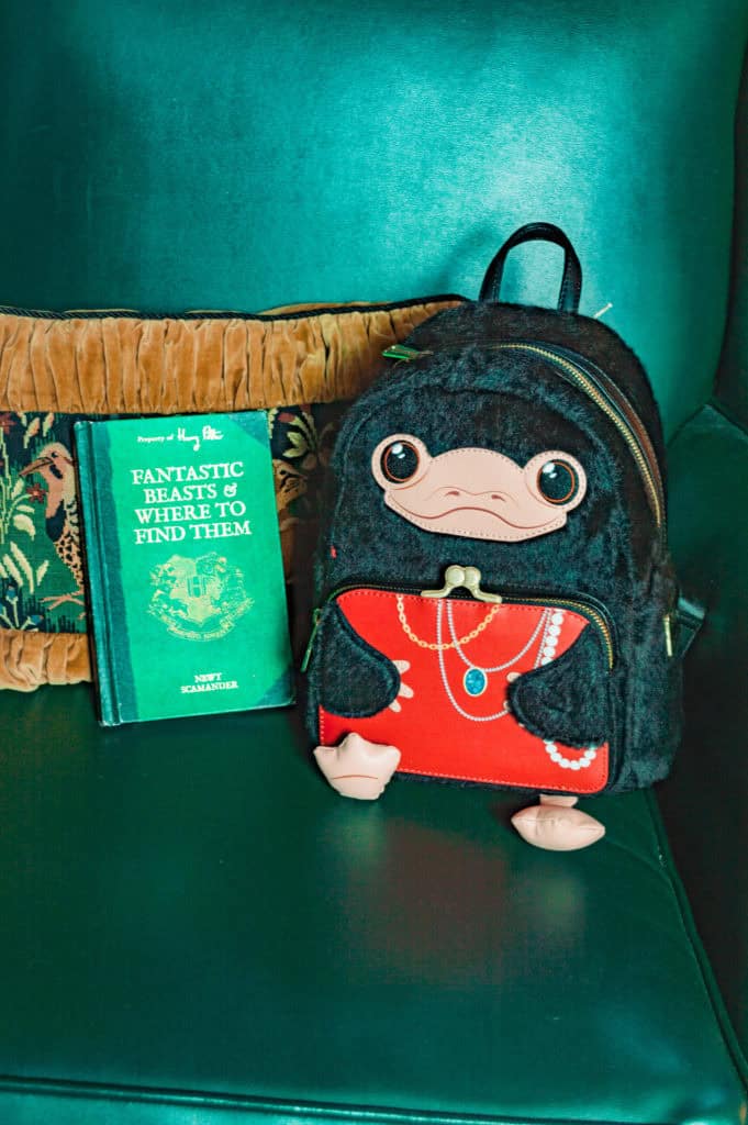 small creature on a backback with Fantastic Beasts and Where to Find Them small green book on a green chair