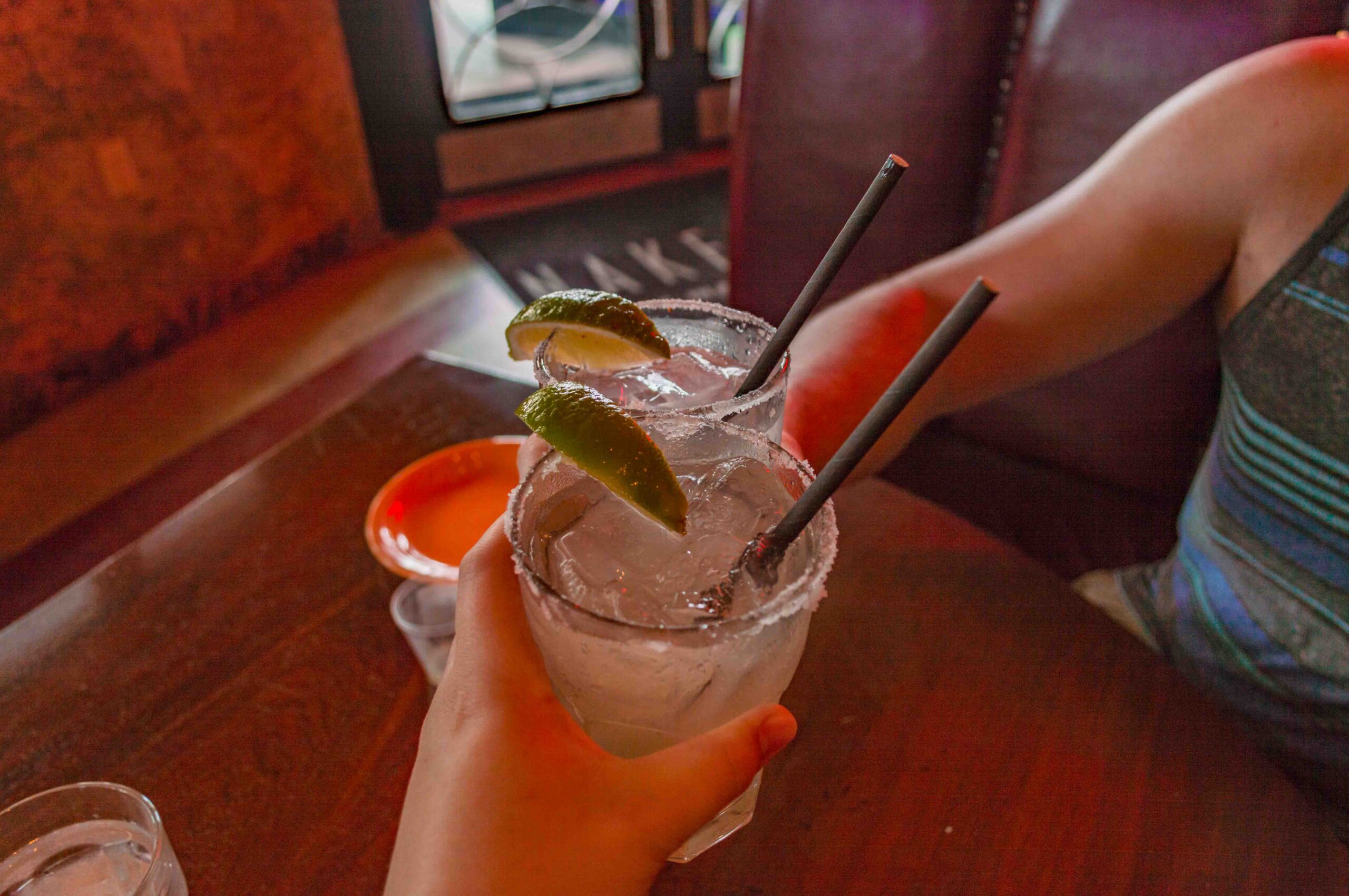 couple clinking margarita drinks in a booth at a restaurant