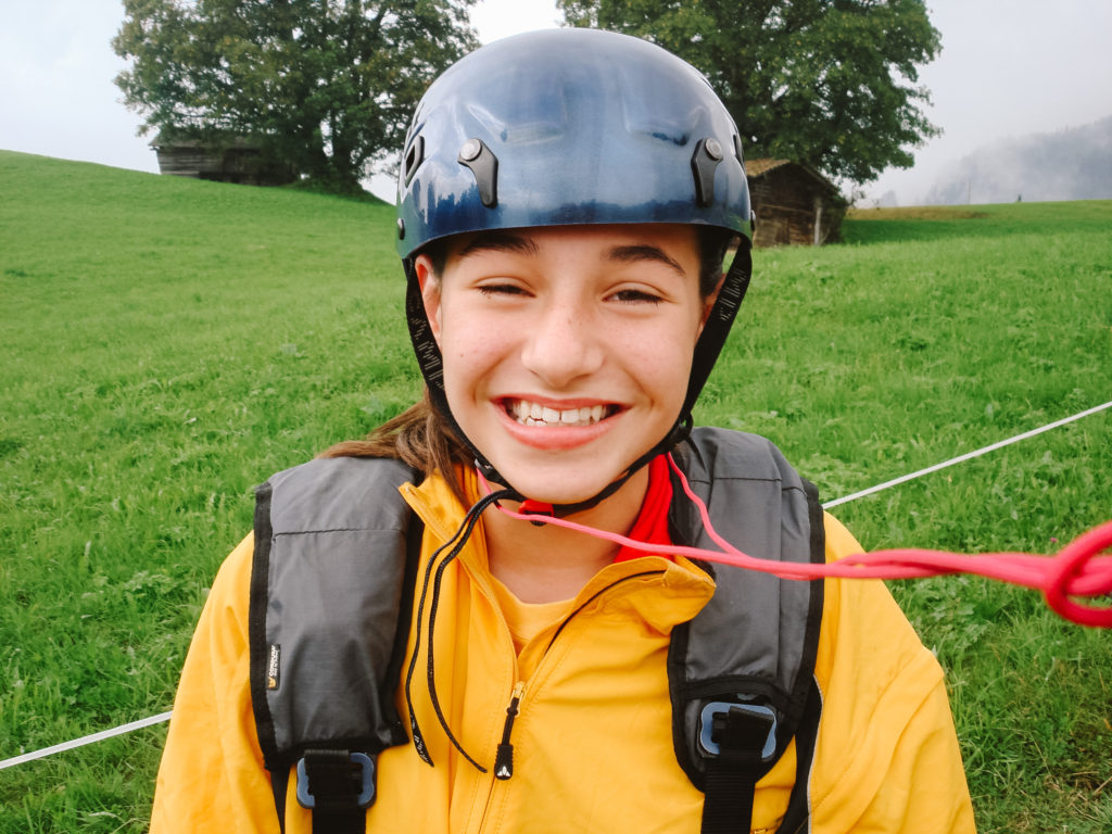 Young girl getting ready for paragliding in Switzerland in a yellow jacket and helmet