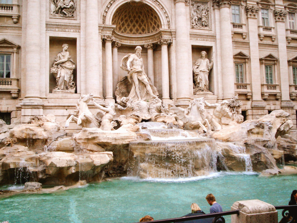 View of the Trevi Fountain from the street level at the top of the stairs with turquoise waters in Rome Italy