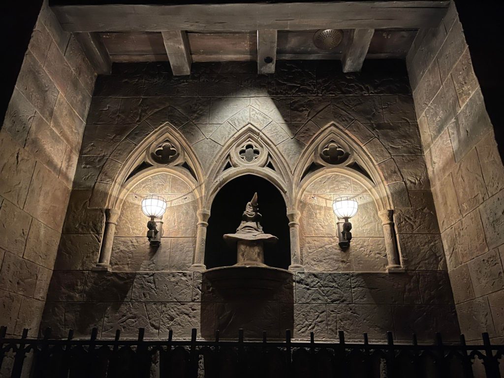sorting hat on a shelf with lamps on each side and three archways in the wall to accent the display