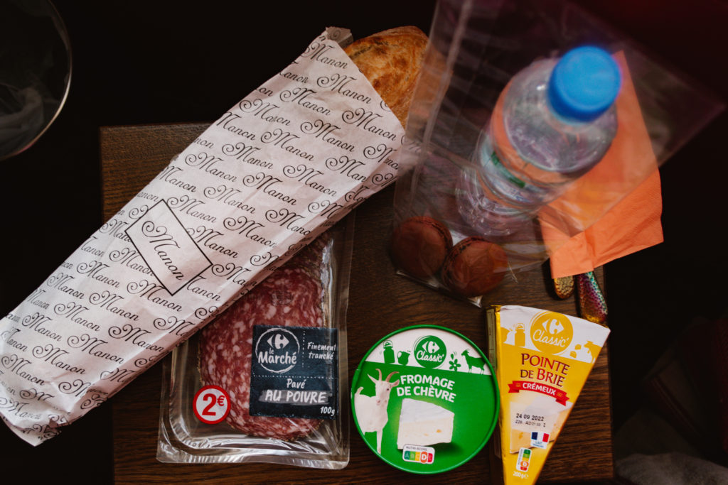 French grocery items including a baguette, meat, cheeses, and macrons.