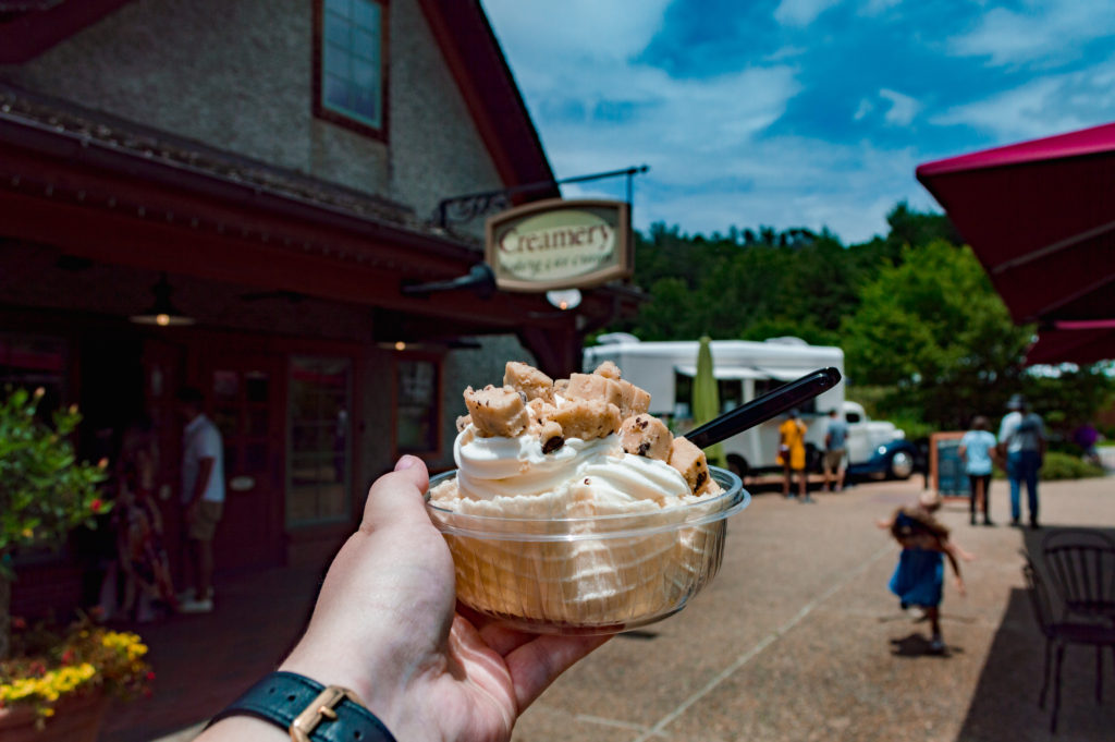 woman holding a vanilla cookie dough ice cream outstretched with Creamery and food truck in the background