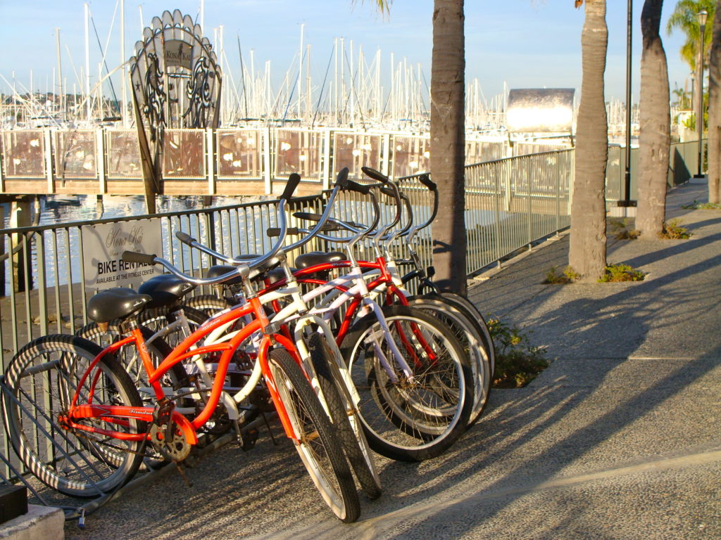 Red bikes parked along a fence in San Diego with a boat marina in the background