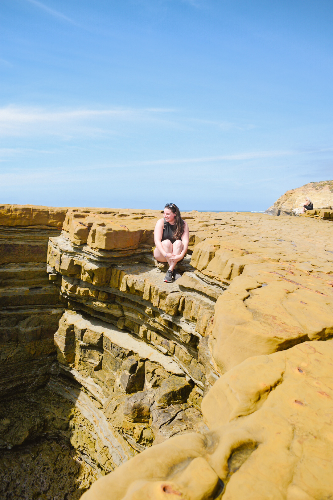 woman sitting on a cliffside looking at ocean below