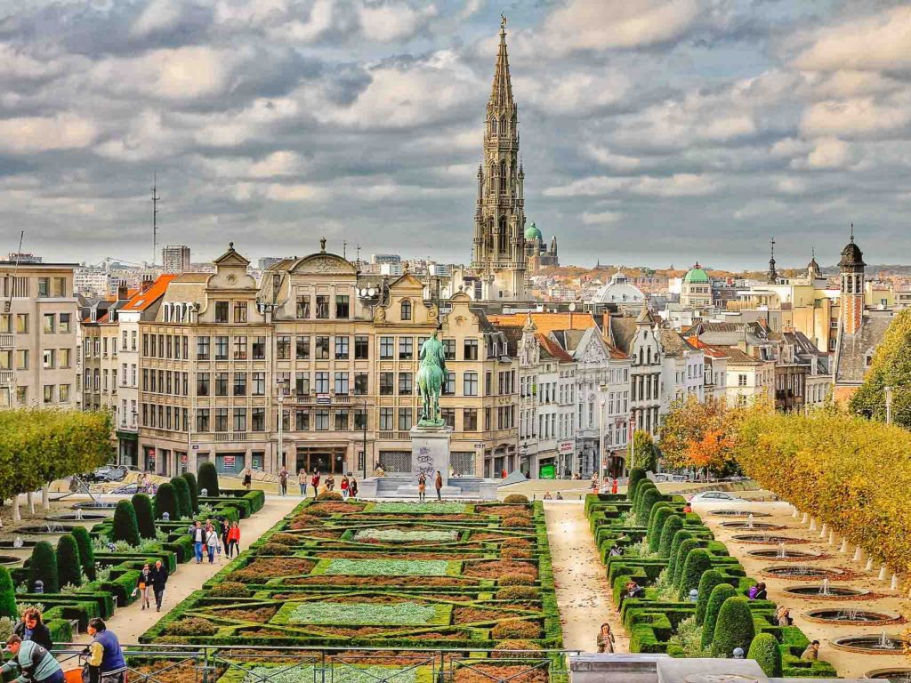 City of Brussels in Belgium with a park in the foreground and residential buildings in the background with a large statue and cathedral