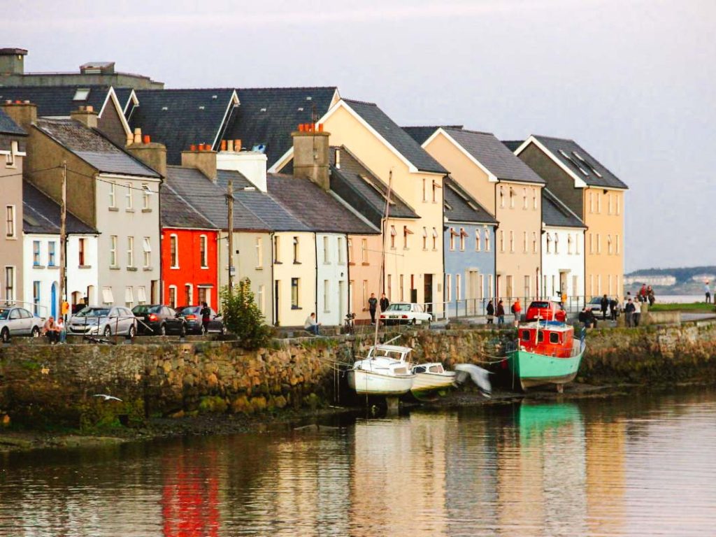 Galway coastal city with colorful homes along the water with two boats docked