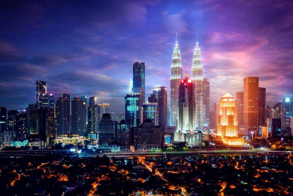Kuala Lumpur at night with towers lit up and a purple dreamy sky