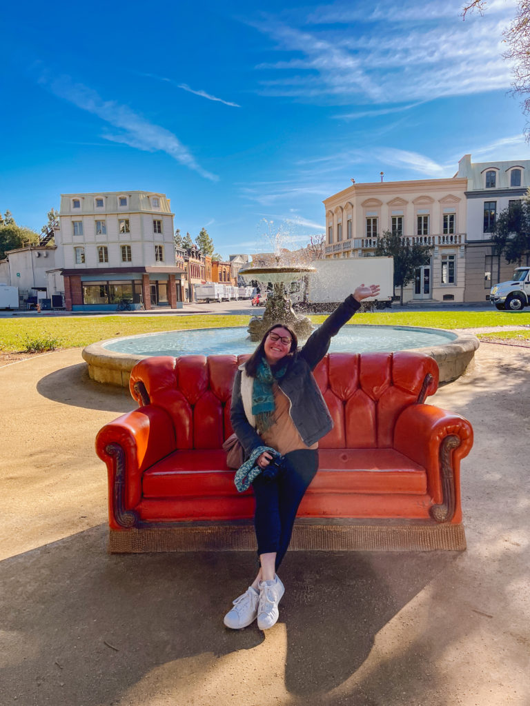 woman posing on the red couch from Friends with the iconic fountain in the background