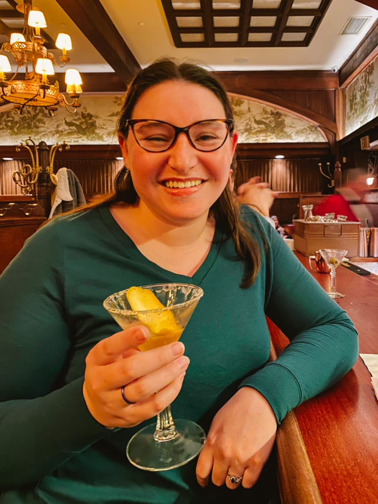woman sitting at a vintage Hollywood bar holding a Sidecar cocktail