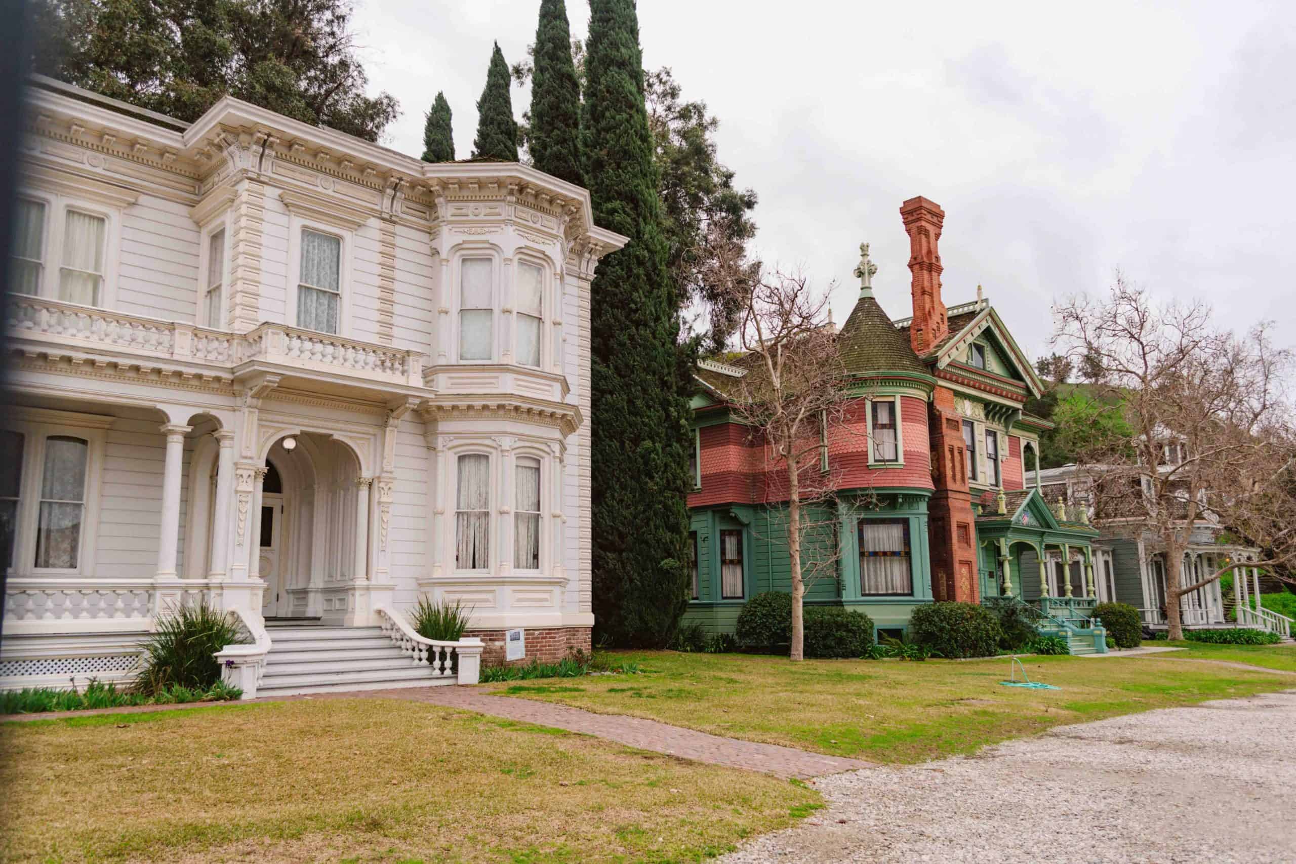 row of Victorian homes with the closest white one and a colorful one next to it