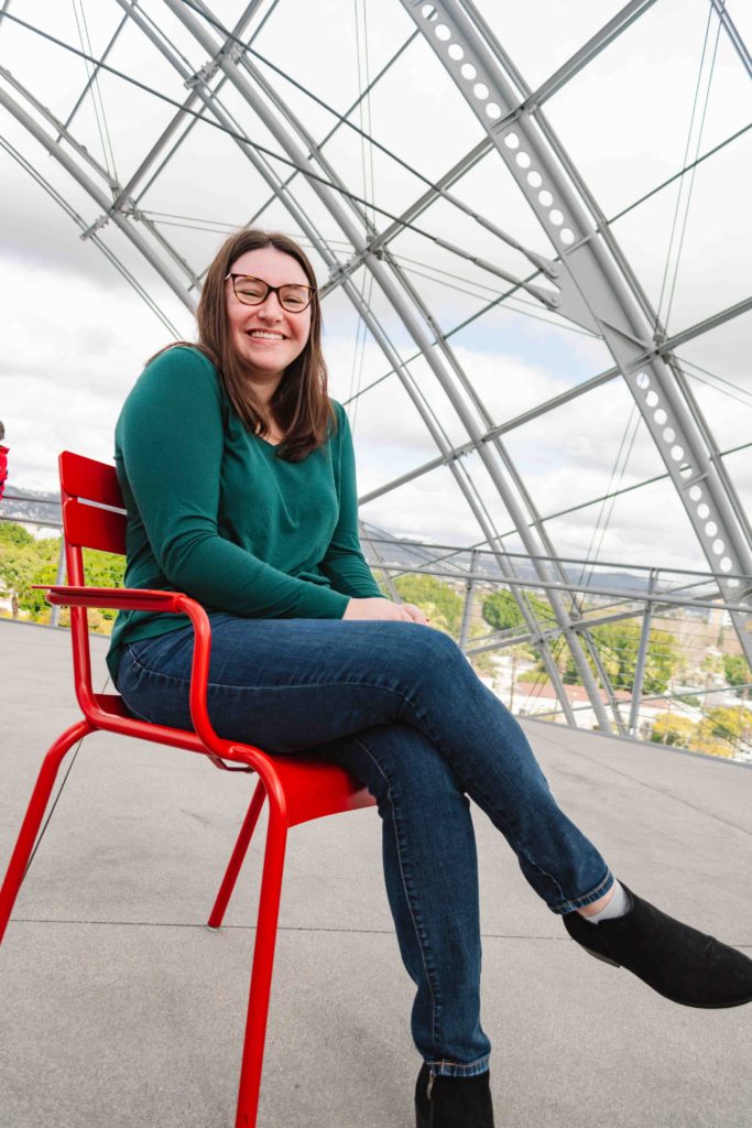 woman posing sitting on a red chair under a covered see-through dome in Los Angeles