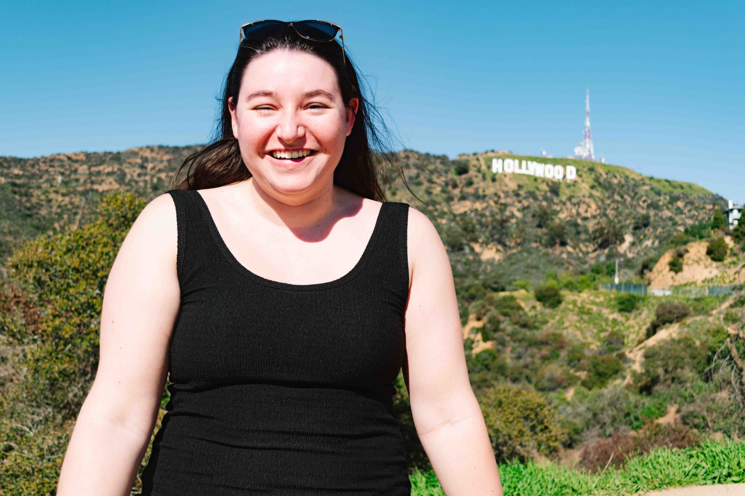 woman smiling facing the sun with the Hollywood sign behind her
