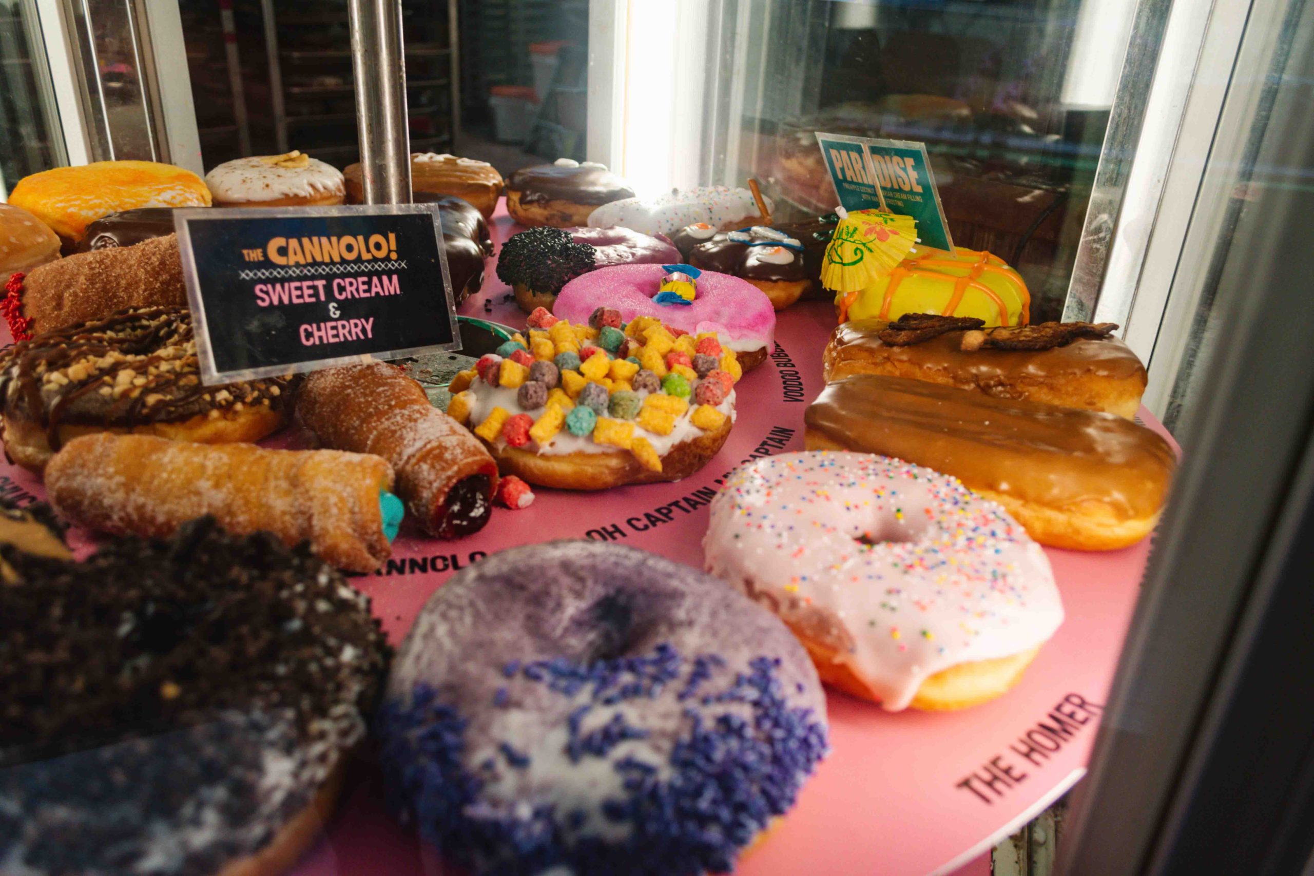 VooDoo donuts on a rotating display with over the top flavors on a pink stand