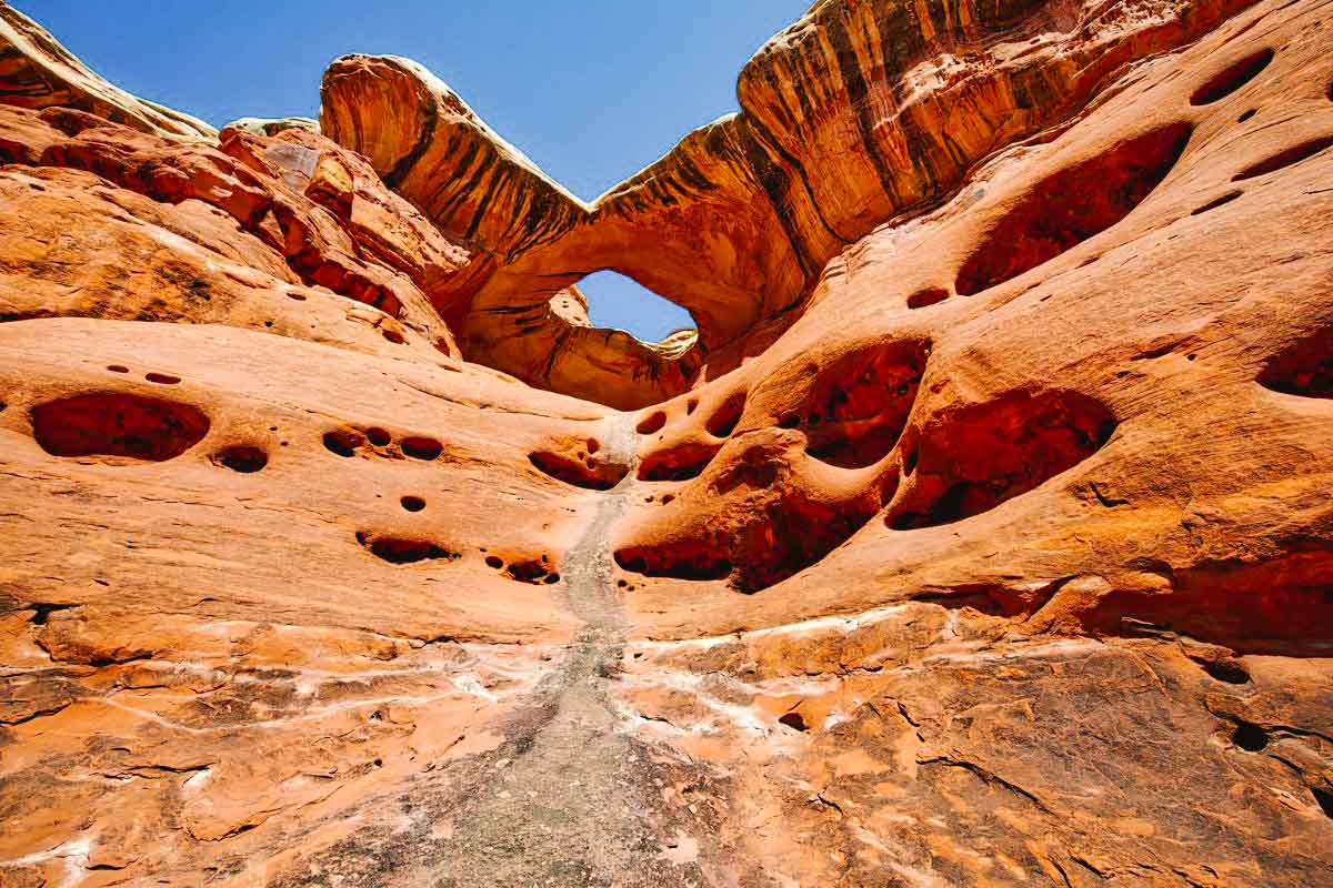 natural arch in red rock with holes also in the rock created from water