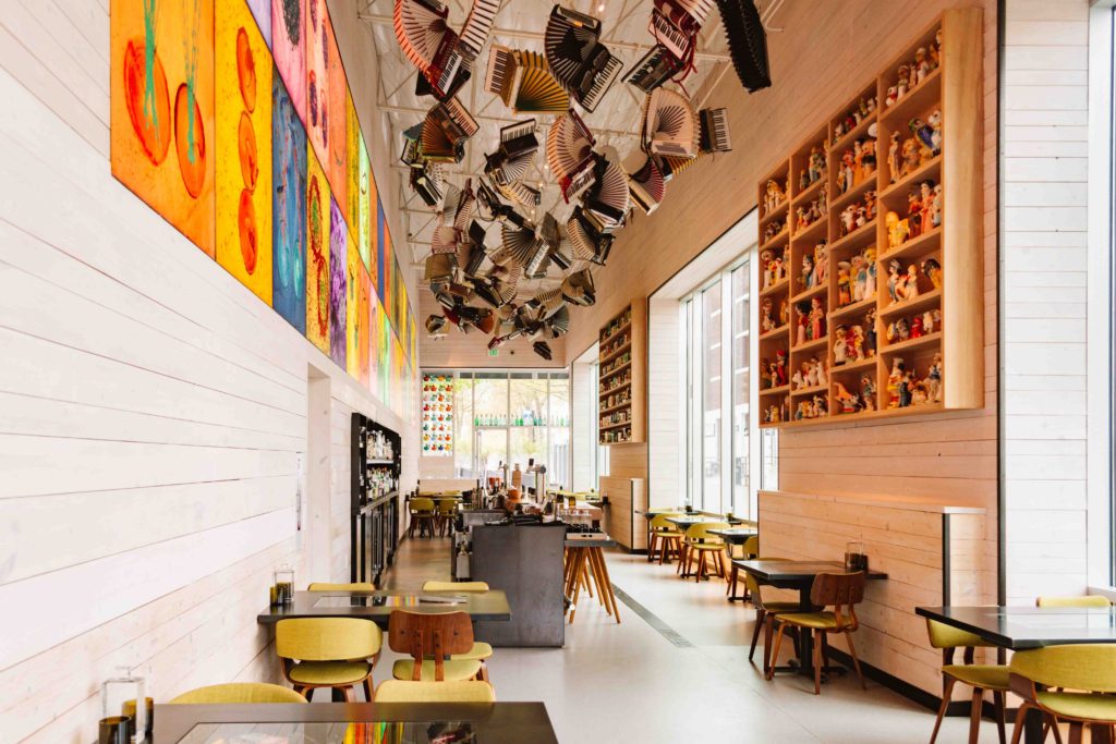 Bright and airy restaurant with a central bar and books hanging from the ceiling with art on the walls