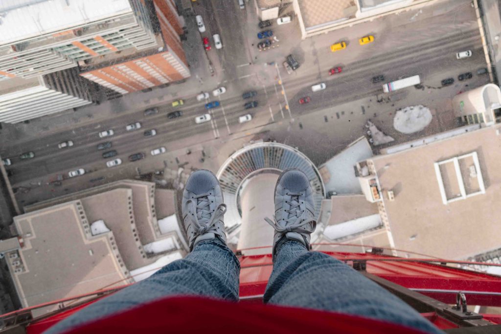 woman's feet over a glass floor on a observation deck of a tower