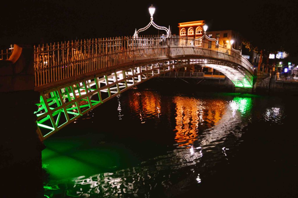 Ha'penny Bridge in Dublin lit up at night with green and white lights underneath