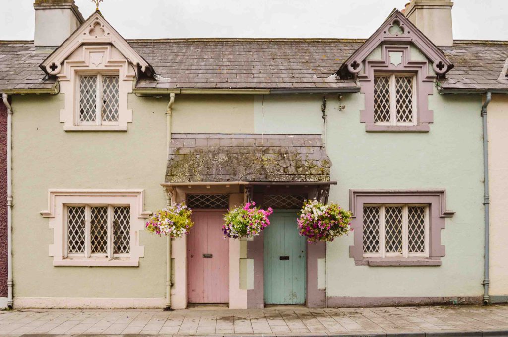 view of two homes with colorful doors and flowers hanging from the overhang over the doors