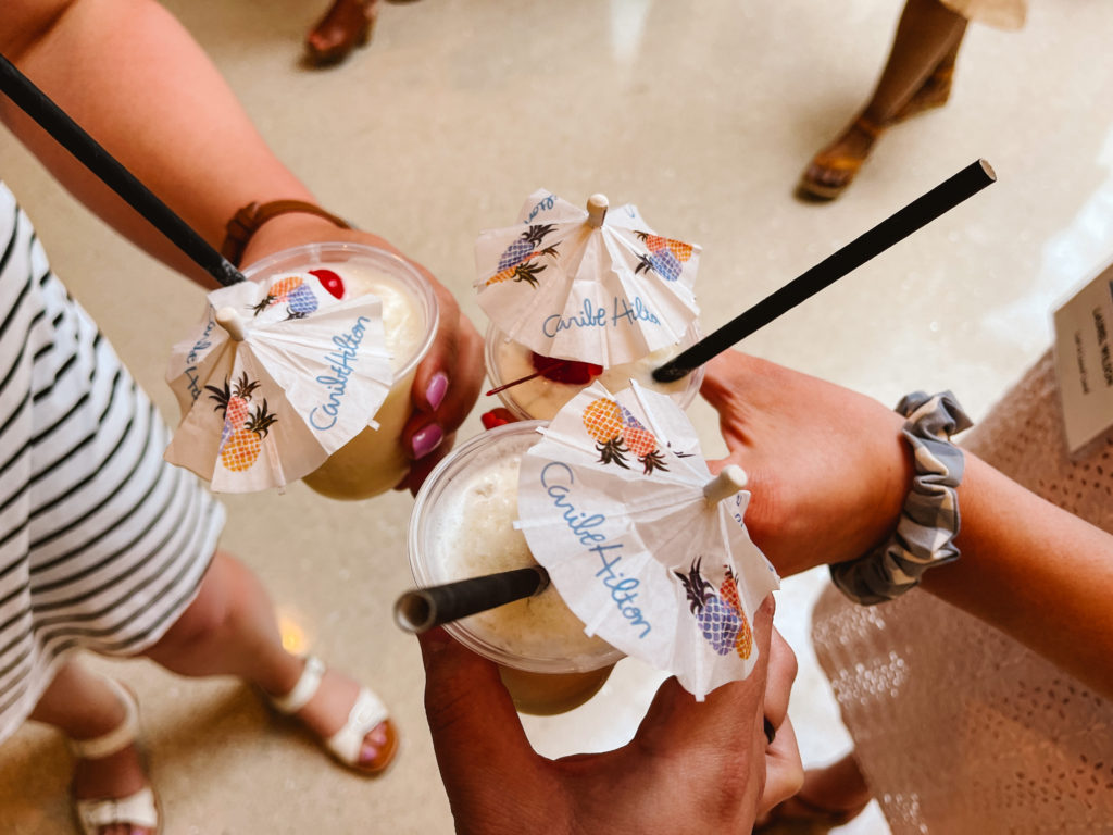 Three women holding and cheers with pina coladas with umbrellas in them