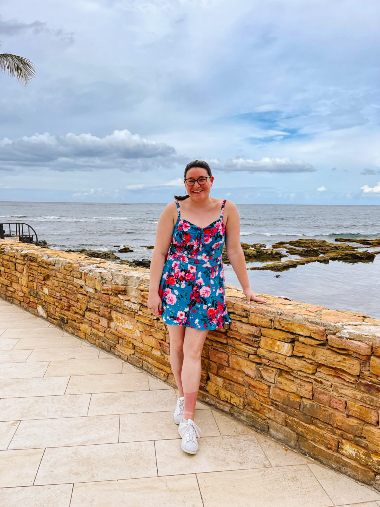 woman standing at a hip-high stone wall with the ocean in the background in San Juan, Puerto Rico