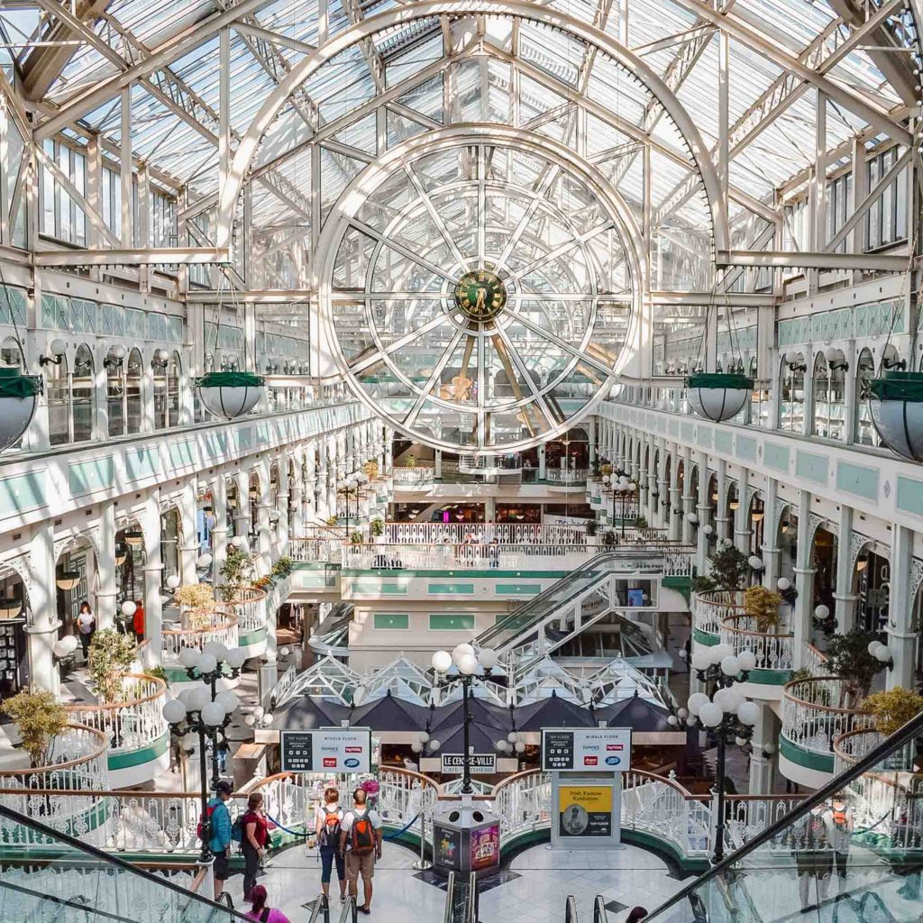 Stephen's Green Shopping Centre in Dublin with glass ceiling, mint green archways and a large glass clock in the center
