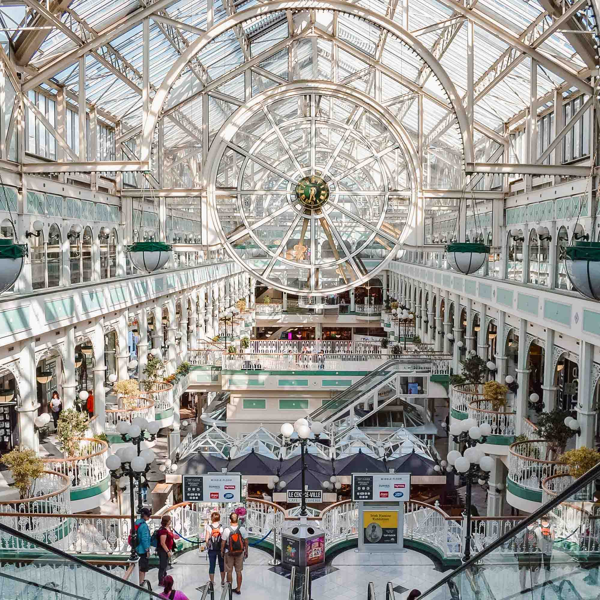 Stephen's Green Shopping Centre in Dublin with glass ceiling, mint green archways and a large glass clock in the center
