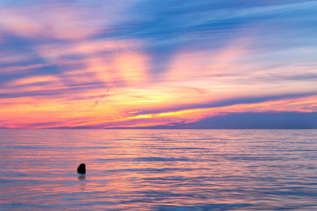 view of Ludington Michigan Lake at sunset with purple, orange, and yellow hues