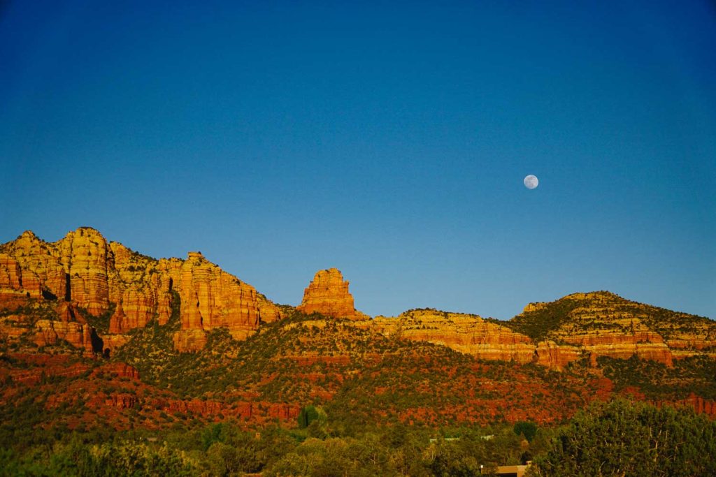 View of Sedona red rocks at twilight with the moon out to the upper right