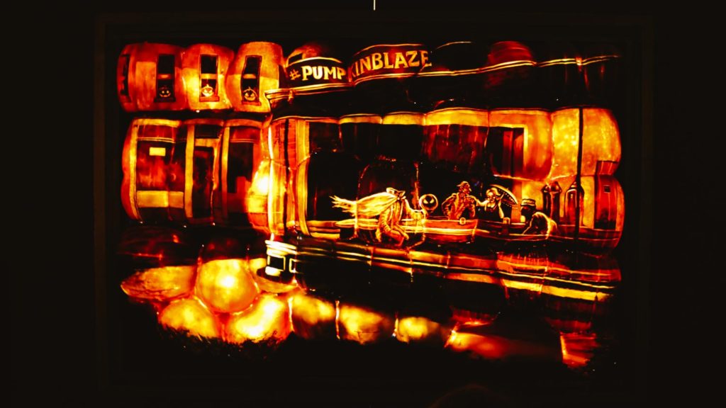 Pumpkins carved to look like a famous painting and lit from behind at night