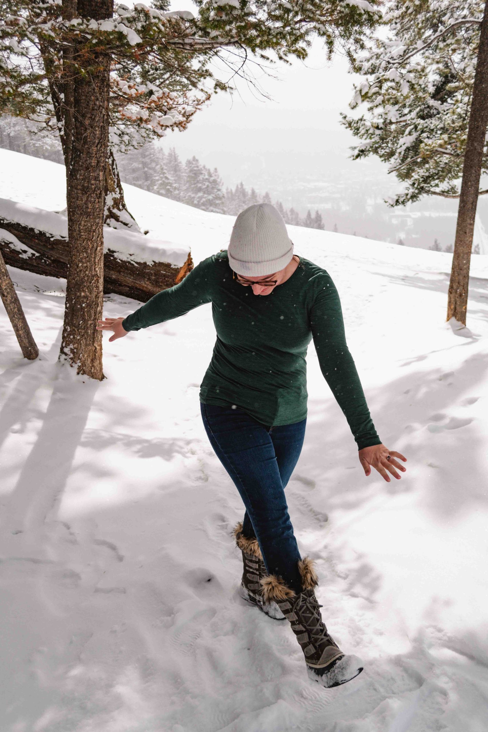 Woman wearing a long sleeved merino wool top dancing in the snow