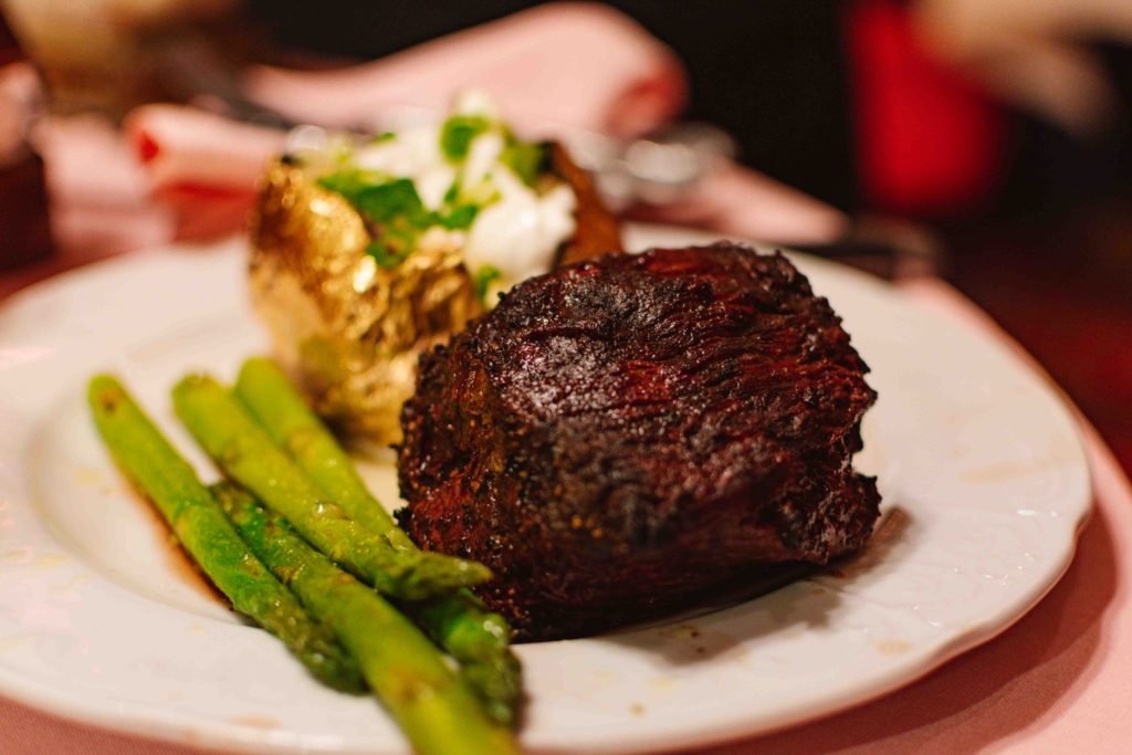 Filet mignon steak with gold foiled baked potato and asparagus.