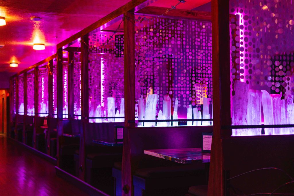Purple lit booths in a bar and restaurant with large crystal pieces in between each booth
