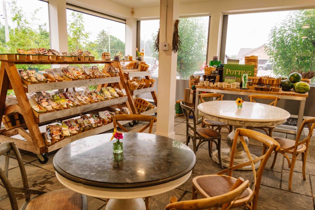 Cafe and farmstand with dried soups on shelves outside and fruit on a table in the back.