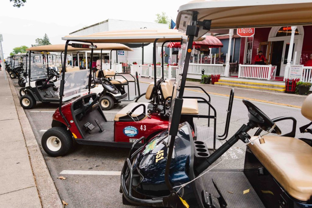 Golf carts parked in a line on the street.