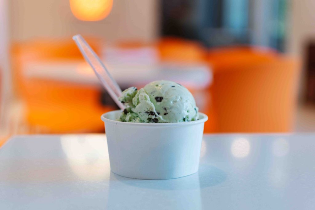 Mint chip ice cream in a cup with spoon sticking out on a white table in UT's Creamery