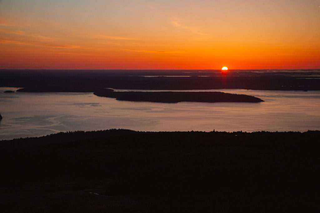 View of a sunset over mountains in the distance in Acadia National Park in Maine