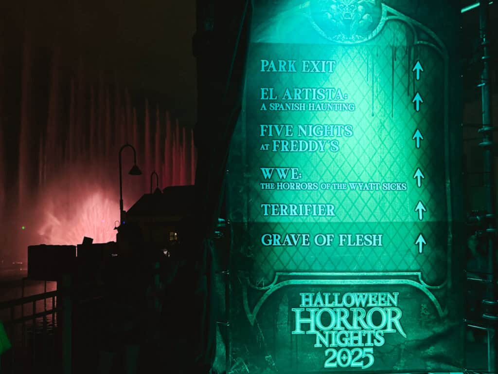 Sign lit up green that tells which direction various haunted houses are in Universal Studios.
