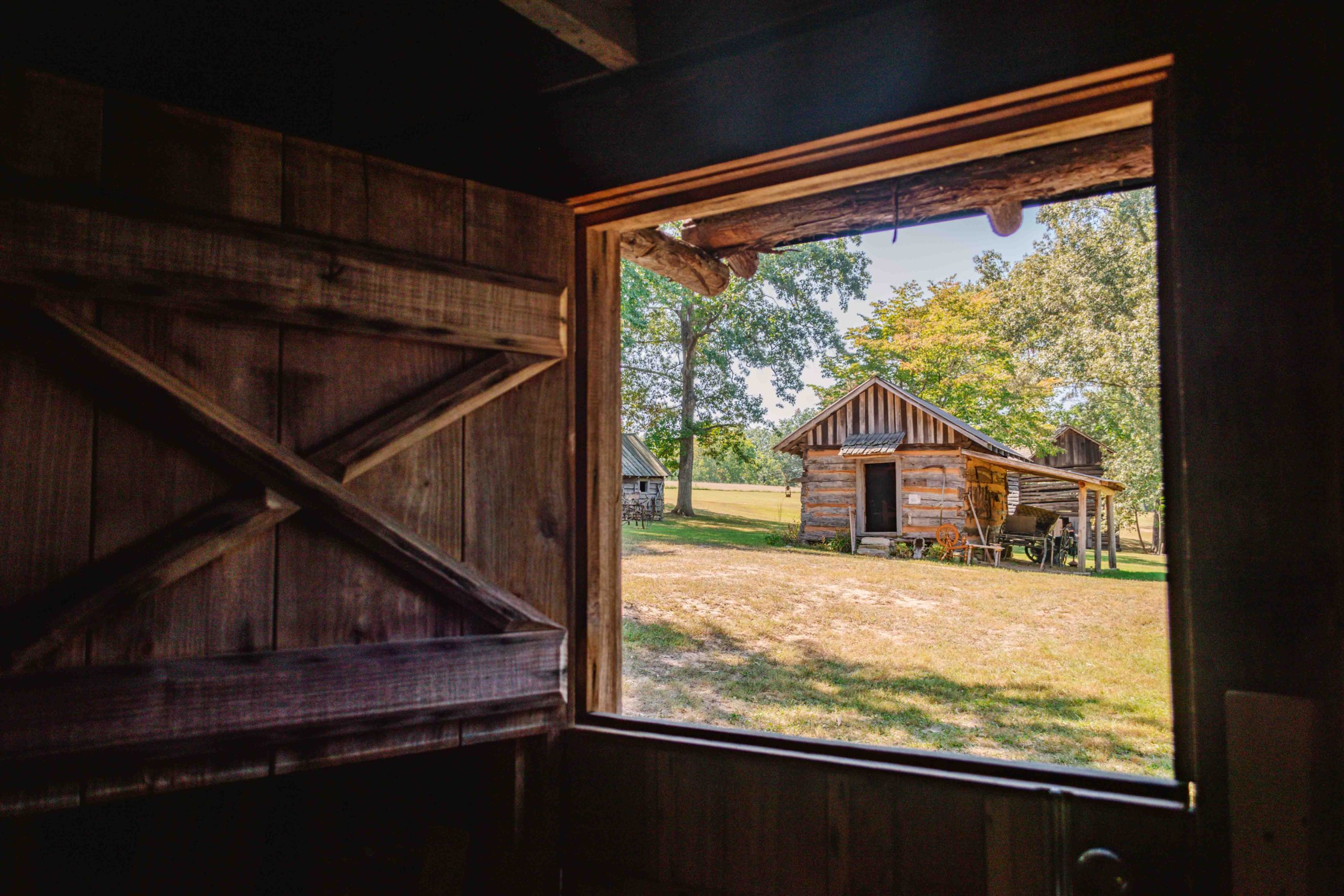 View looking out a window in a wooden home from the 19th century at another historic structure