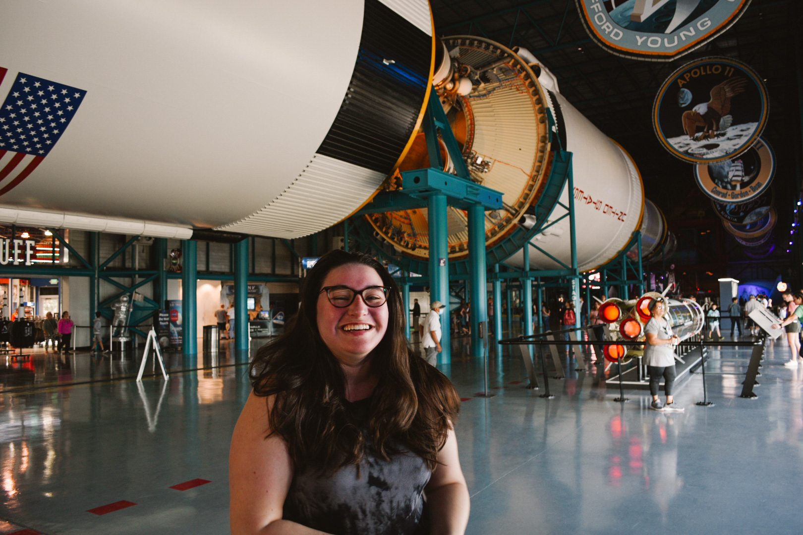 Woman smiling under the Saturn V rocket in a museum complex