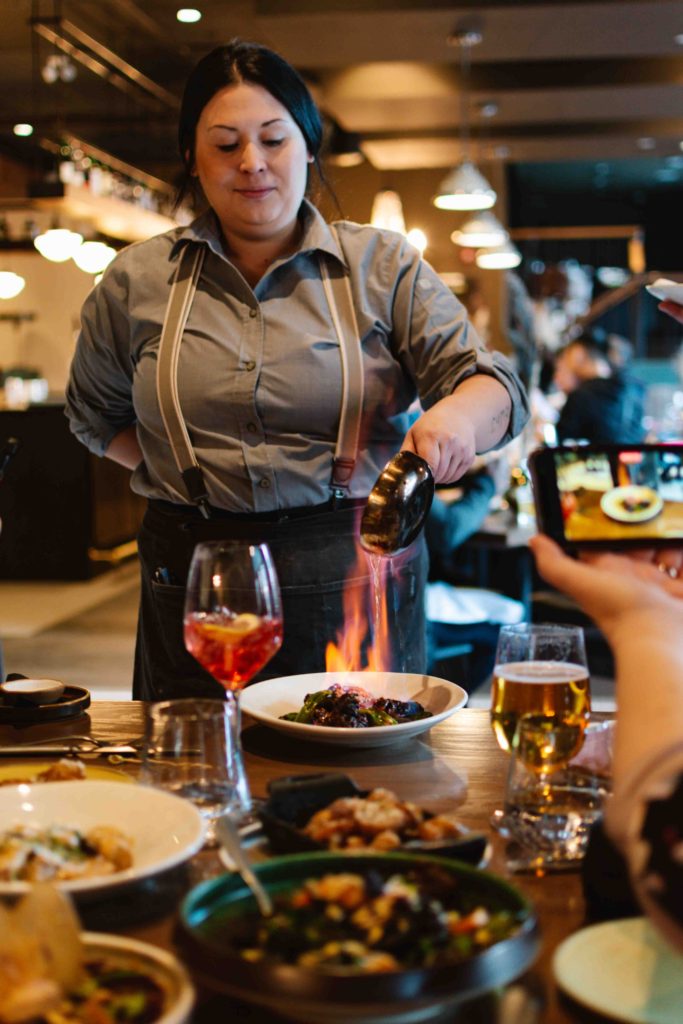 Woman pouring enflamed syrup on ginger beef at a high scale modern restaurant in downtown Banff in Alberta Canada