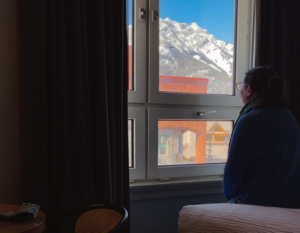 woman looking out a window at snowy mountains in Canada Alberta