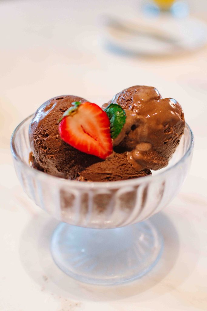 three scoops of chocolate ice cream in a cold elevated ice cream bowl with a sliced strawberry on top; a uniquely Nashville dish to try at the Conrad