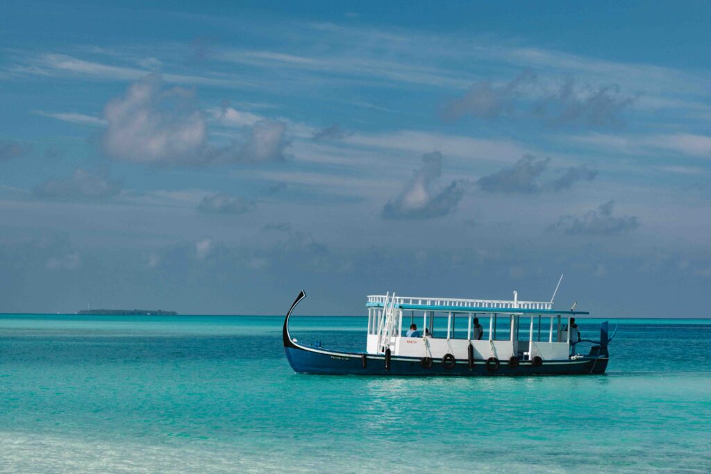 Small passenger boat traveling on beautiful turquoise water in the Maldives.